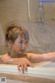 A woman taking a bath in a bathtub with water droplets.