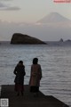 Two women walking along a pier with a mountain in the background.