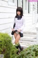 A young woman in a school uniform is posing for the camera.