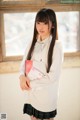 A young woman in a school uniform holding a book.